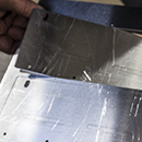Close up on one unformed brackets being removed from the sheet metal